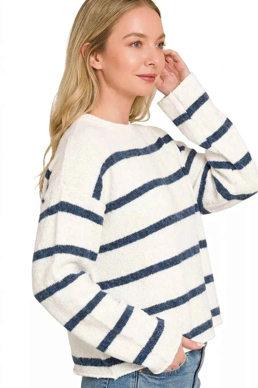 Woman wearing an ivory lightweight wool blend sweater with navy stripes by Zenana paired with blue jeans. Side View