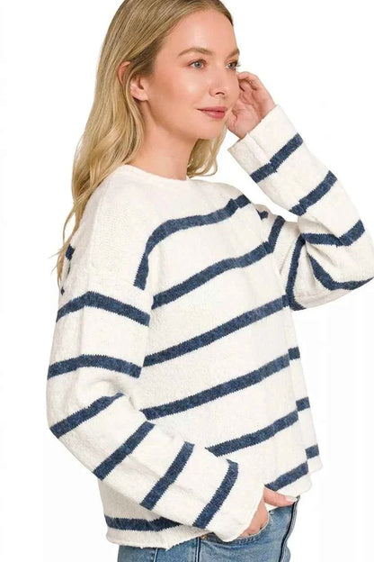 Woman wearing an ivory lightweight wool blend sweater with navy stripes by Zenana paired with blue jeans. Side View