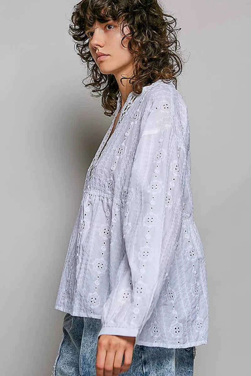 Woman wearing an off white POL cotton blouse with eyelet embroidery, lace detailing, and a split neckline.
 Side View