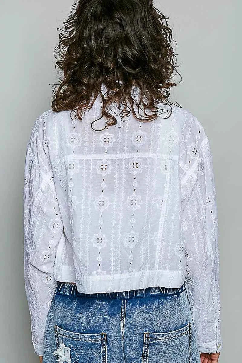 Woman wearing an off white eyelet textured cotton cropped button-front jacket by POL with relaxed denim jeans. back view