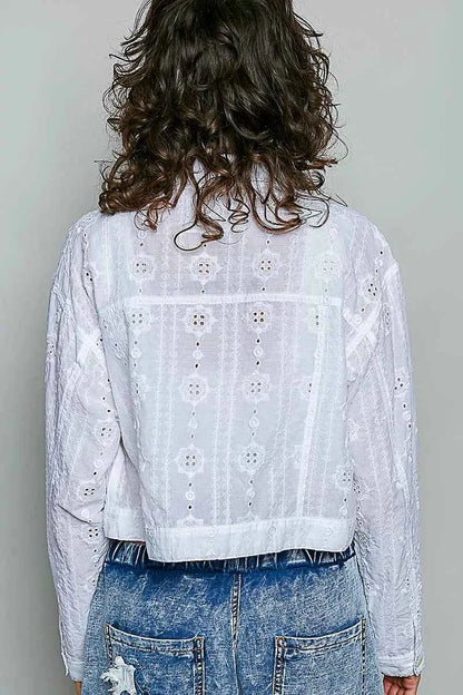 Woman wearing an off white eyelet textured cotton cropped button-front jacket by POL with relaxed denim jeans. back view