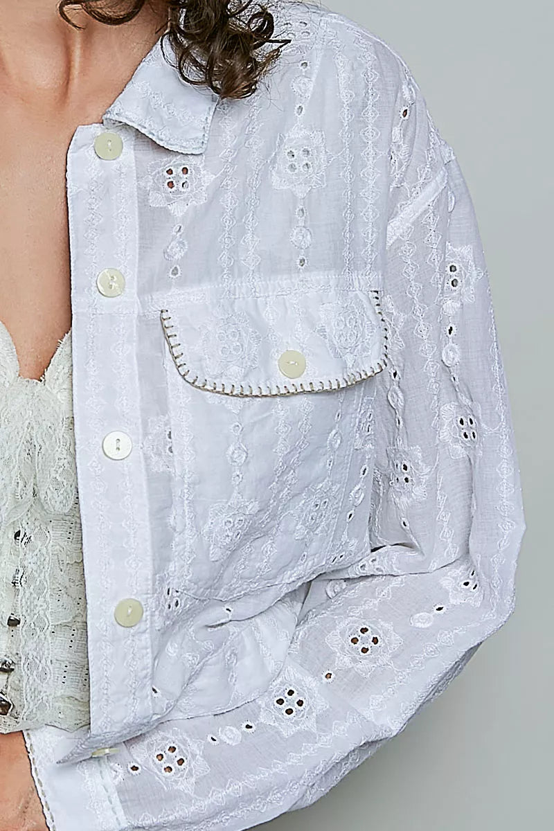 Woman wearing an off white eyelet textured cotton cropped button-front jacket by POL with relaxed denim jeans. close view