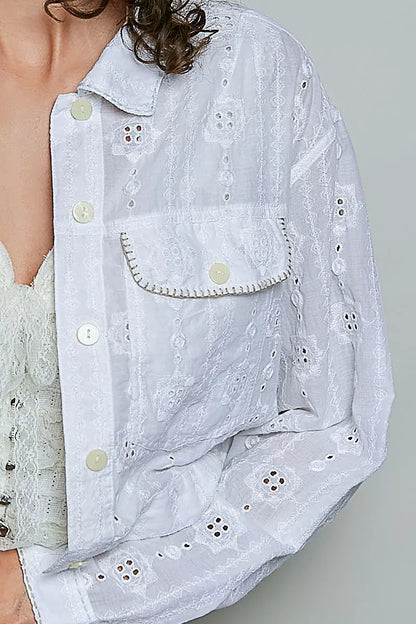 Woman wearing an off white eyelet textured cotton cropped button-front jacket by POL with relaxed denim jeans. close view
