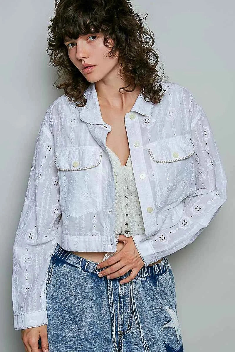 Woman wearing an off white eyelet textured cotton cropped button-front jacket by POL with relaxed denim jeans. front view 2