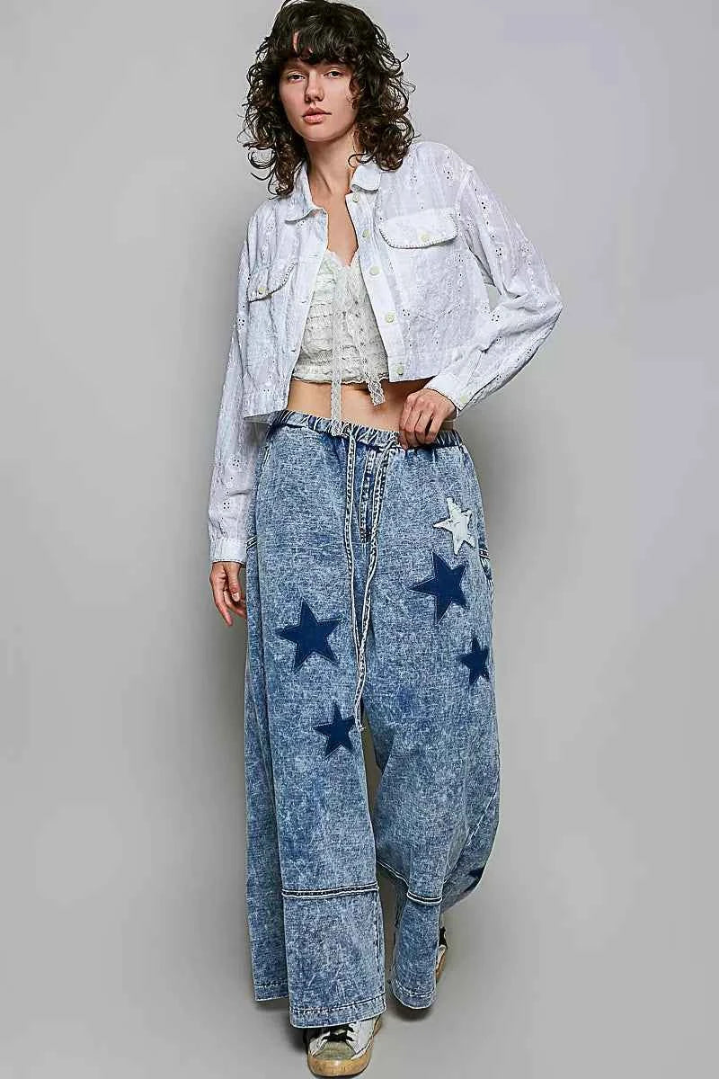 Woman wearing an off white eyelet textured cotton cropped button-front jacket by POL with relaxed denim jeans. full view