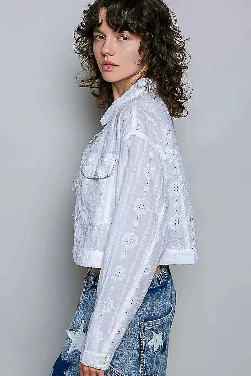 Woman wearing an off white eyelet textured cotton cropped button-front jacket by POL with relaxed denim jeans. side view