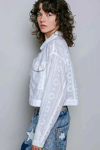 Woman wearing an off white eyelet textured cotton cropped button-front jacket by POL with relaxed denim jeans. side view