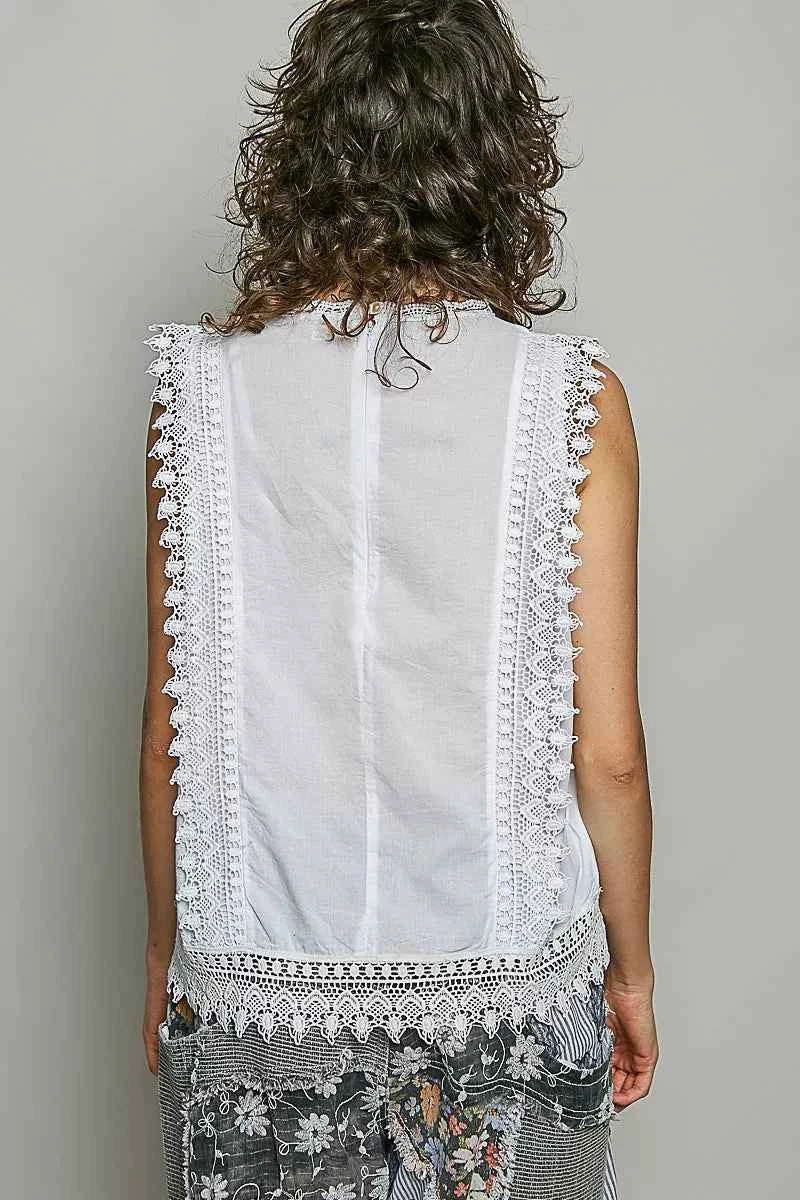 Woman wearing an off white sleeveless cotton top featuring botanical embroidery and scalloped lace trim by POL. Back View