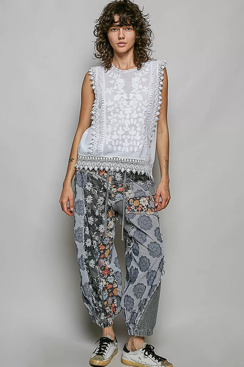 Woman wearing an off white sleeveless cotton top featuring botanical embroidery and scalloped lace trim by POL. Full View