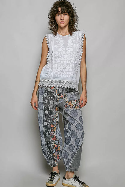 Woman wearing an off white sleeveless cotton top featuring botanical embroidery and scalloped lace trim by POL. Full View