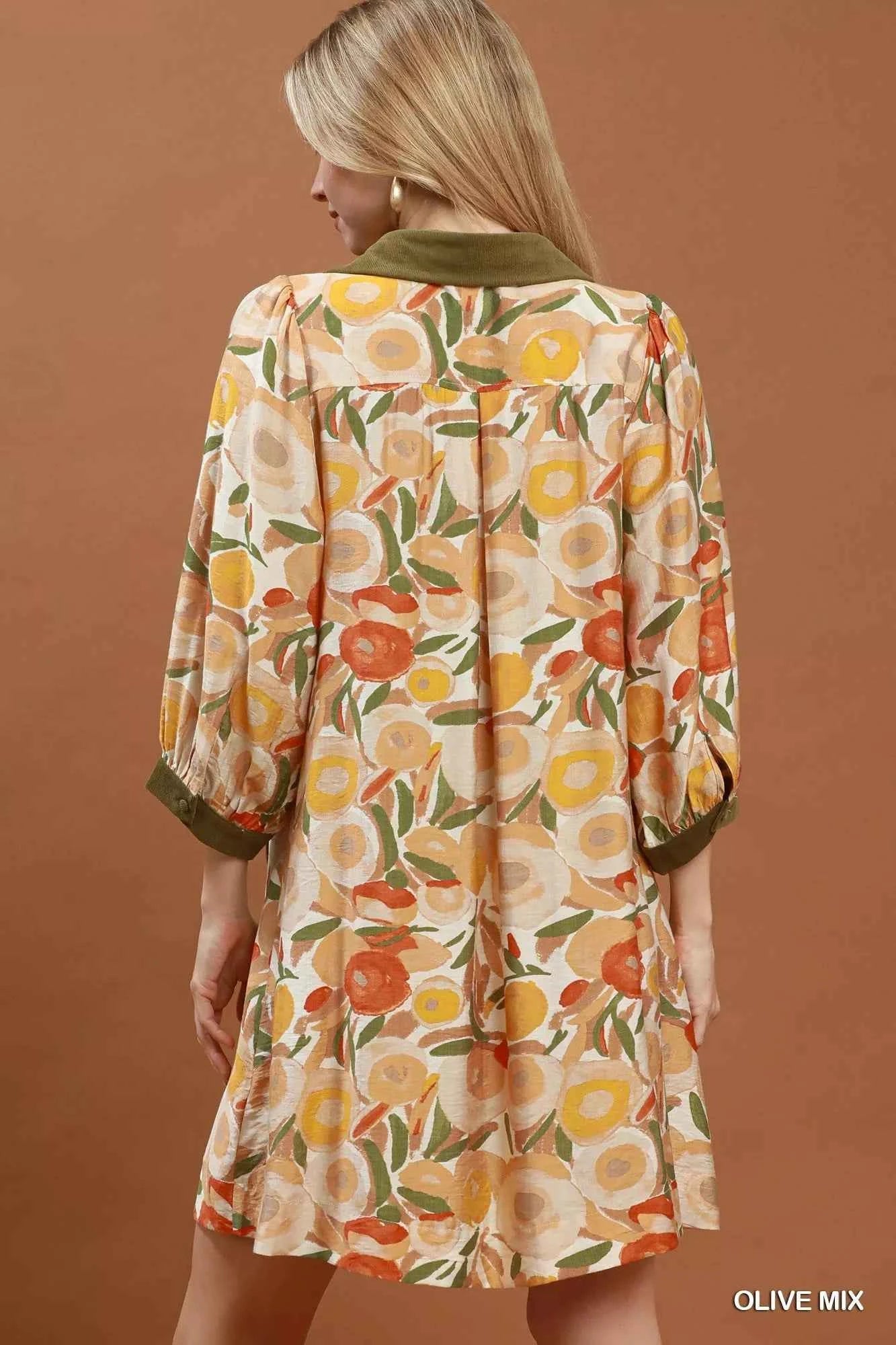 Woman wearing an olive floral contrast trim shift mini dress by Umgee featuring a relaxed silhouette, side pockets, three-quarter sleeves, and watercolor floral print. back view
