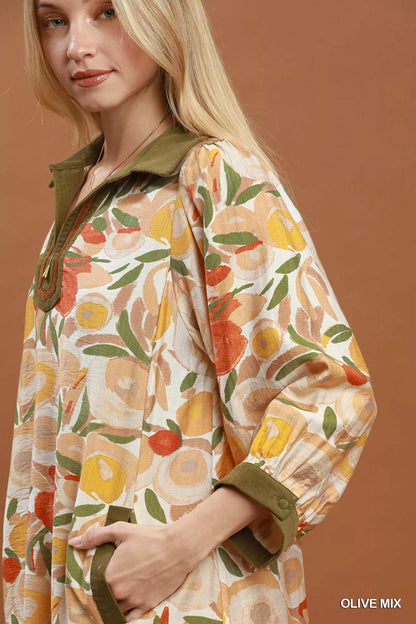 Woman wearing an olive floral contrast trim shift mini dress by Umgee featuring a relaxed silhouette, side pockets, three-quarter sleeves, and watercolor floral print. close view