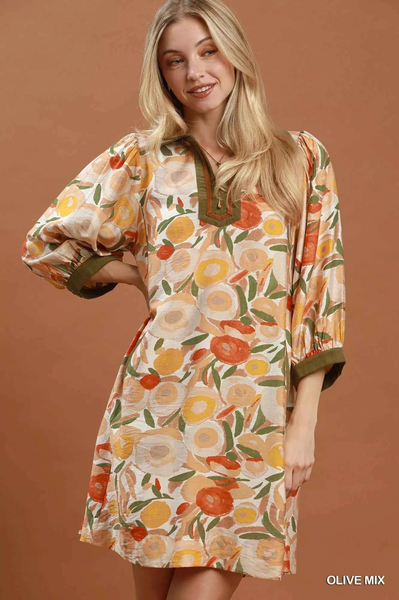 Woman wearing an olive floral contrast trim shift mini dress by Umgee featuring a relaxed silhouette, side pockets, three-quarter sleeves, and watercolor floral print. front view