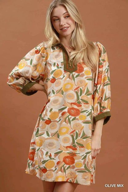 Woman wearing an olive floral contrast trim shift mini dress by Umgee featuring a relaxed silhouette, side pockets, three-quarter sleeves, and watercolor floral print. front view