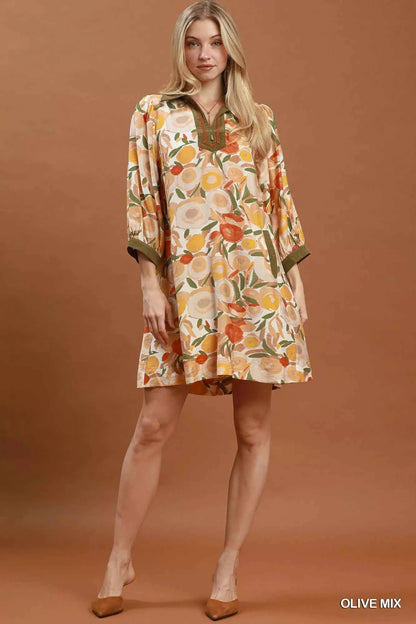 Woman wearing an olive floral contrast trim shift mini dress by Umgee featuring a relaxed silhouette, side pockets, three-quarter sleeves, and watercolor floral print. full view