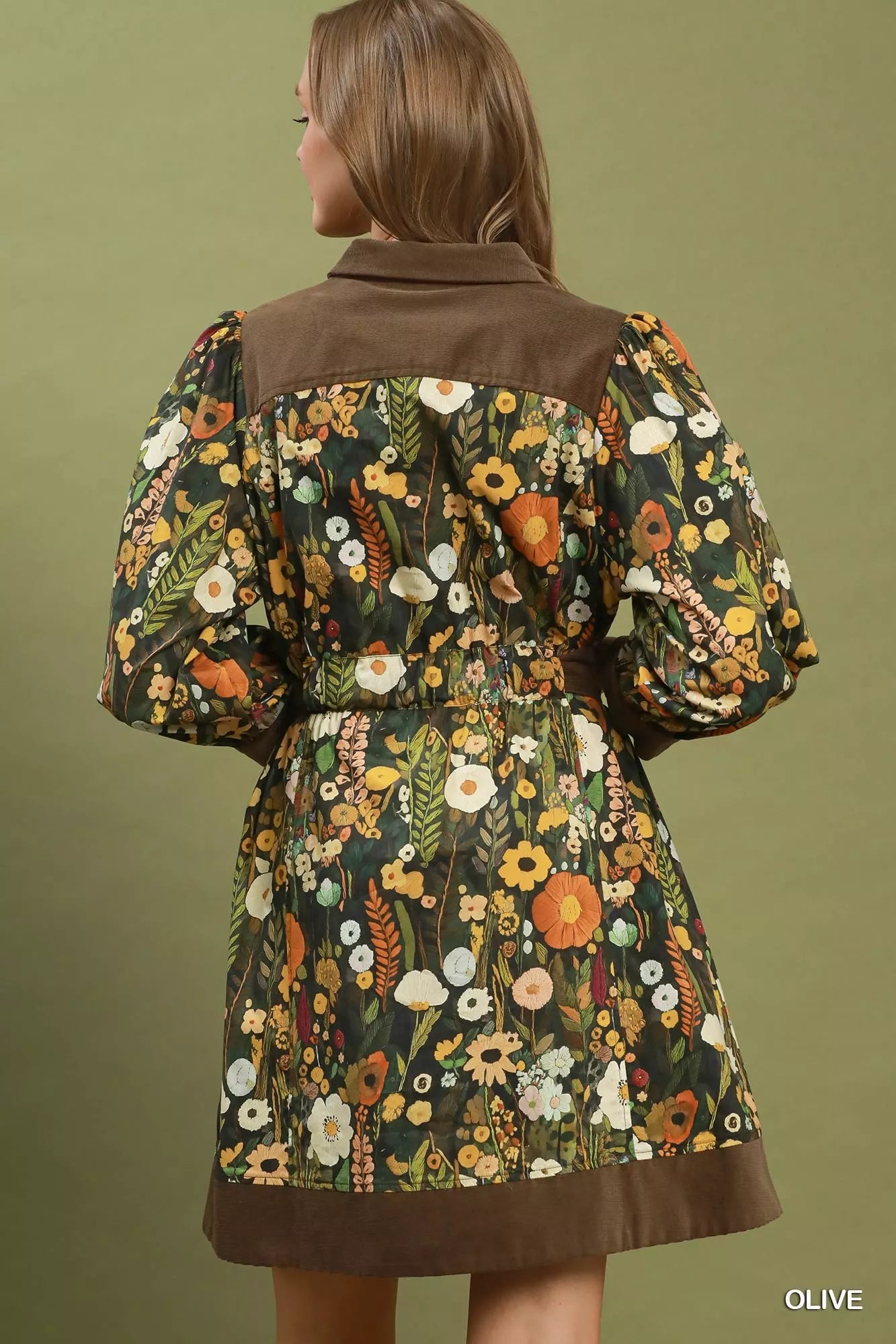 Woman wearing an olive floral print mini dress by Umgee featuring a collared neckline, puff sleeves, button-front detail, and a removable tie waist belt. back view
