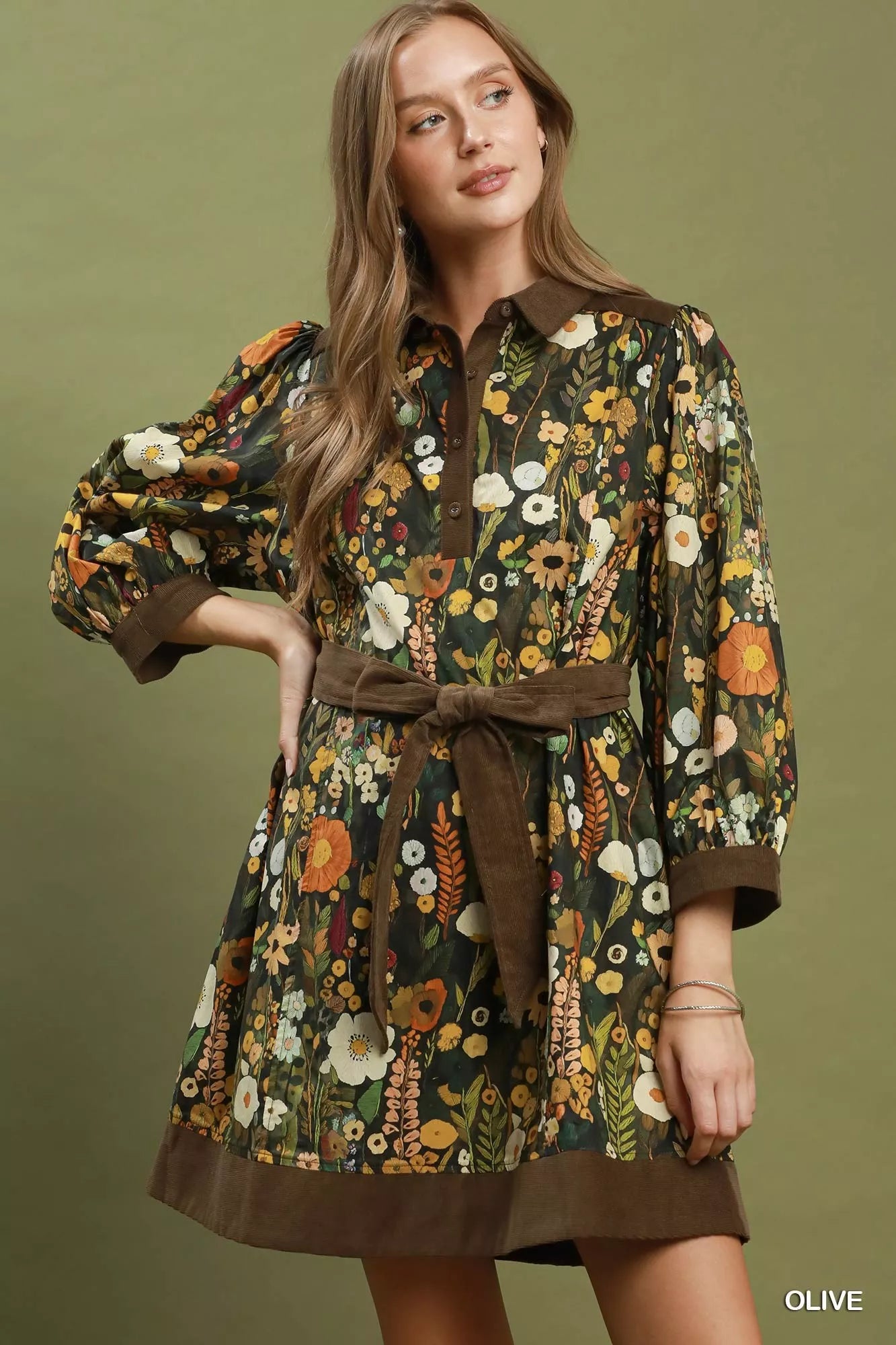 Woman wearing an olive floral print mini dress by Umgee featuring a collared neckline, puff sleeves, button-front detail, and a removable tie waist belt. front view