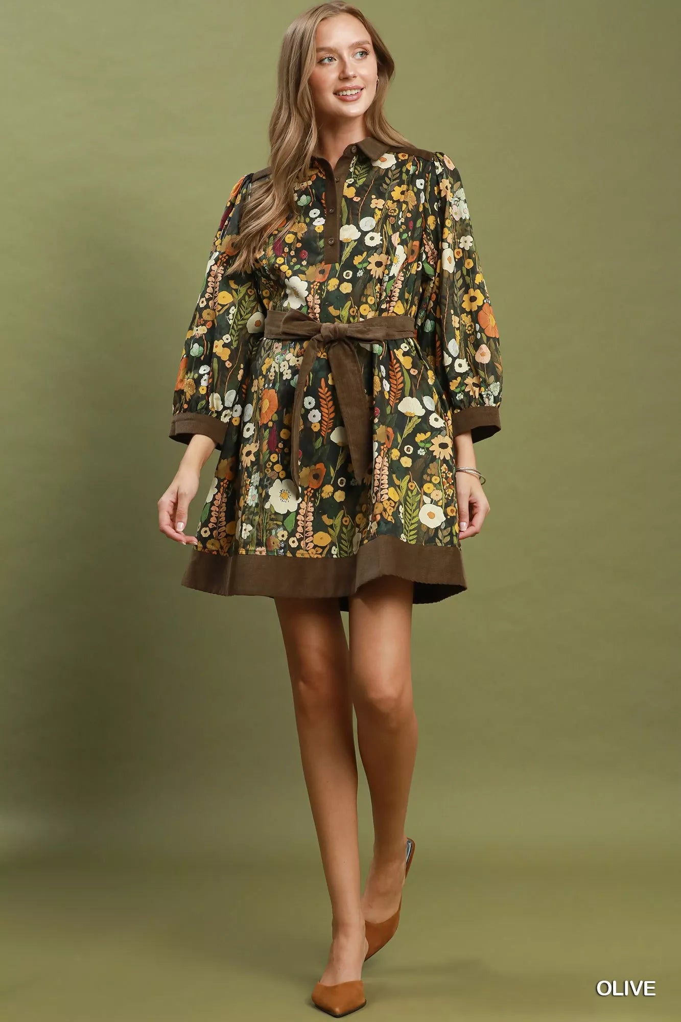 Woman wearing an olive floral print mini dress by Umgee featuring a collared neckline, puff sleeves, button-front detail, and a removable tie waist belt. full view