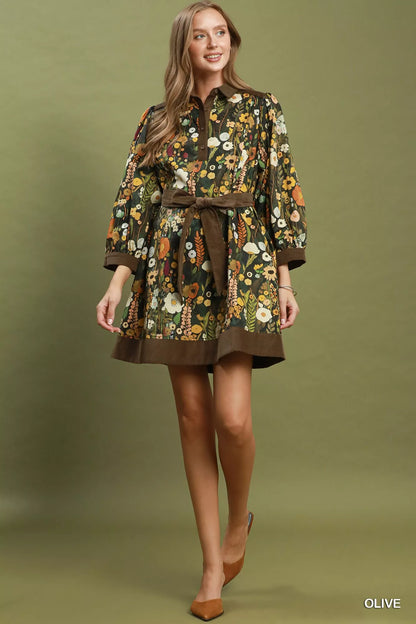 Woman wearing an olive floral print mini dress by Umgee featuring a collared neckline, puff sleeves, button-front detail, and a removable tie waist belt. full view
