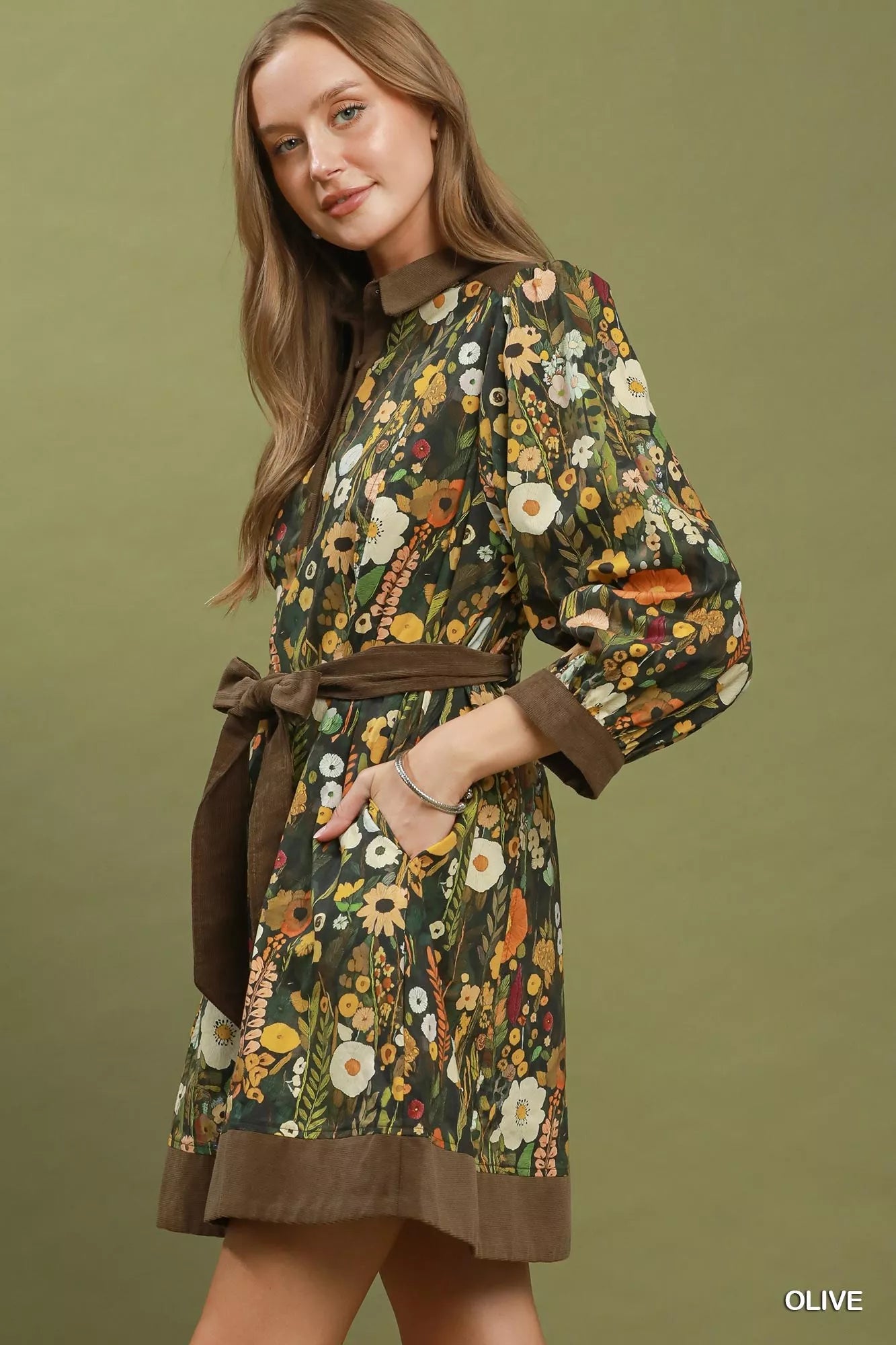 Woman wearing an olive floral print mini dress by Umgee featuring a collared neckline, puff sleeves, button-front detail, and a removable tie waist belt. side view