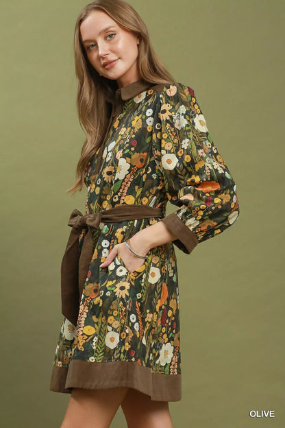 Woman wearing an olive floral print mini dress by Umgee featuring a collared neckline, puff sleeves, button-front detail, and a removable tie waist belt. side view