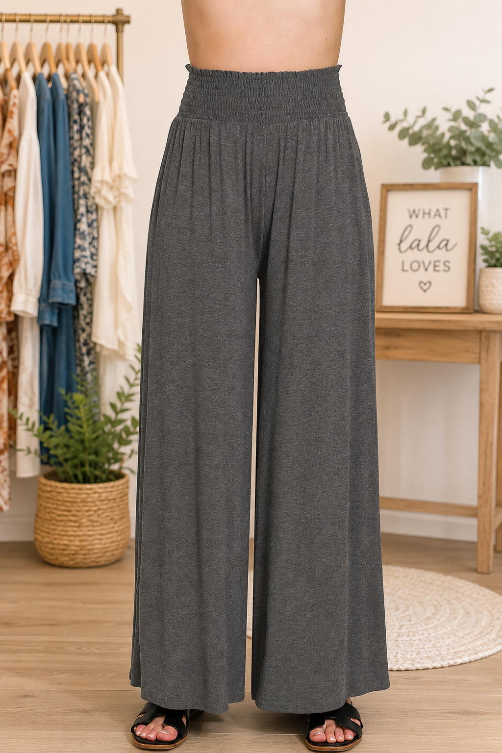 Woman wearing charcoal smocked waist wide leg palazzo pants with a relaxed flowy silhouette and comfortable everyday style. Front view