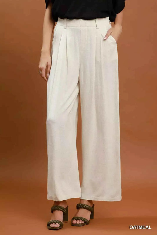 Woman wearing oatmeal high-waisted linen blend wide leg trousers with pleated front and pockets by Umgee. Front View