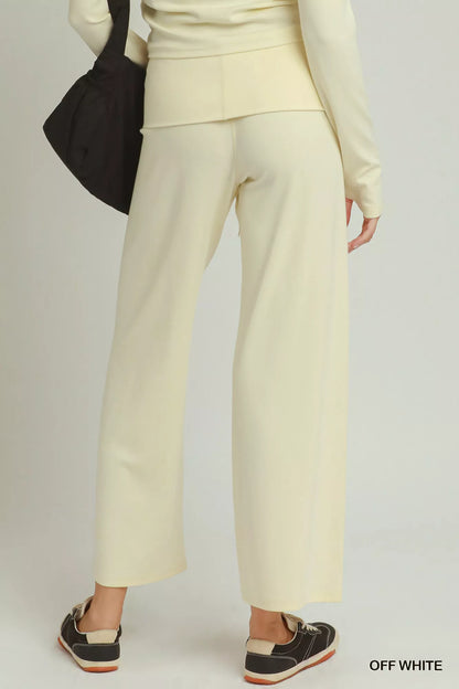 Woman wearing off white straight-leg pants by Umgee styled with black sneakers and a coordinating knit top. Back View