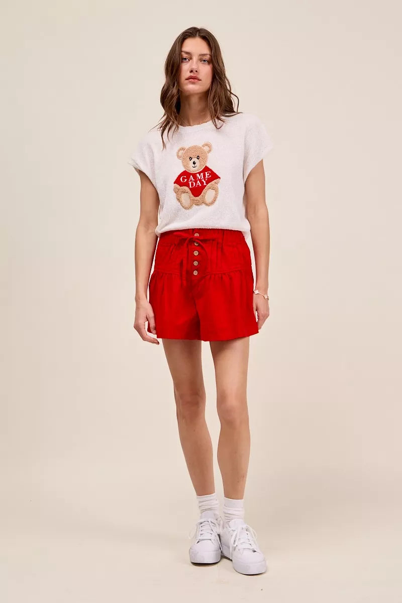 Woman wearing red high waist shorts with pintuck detailing, button-front accents, elastic waistband, and adjustable waist tie. full View 2