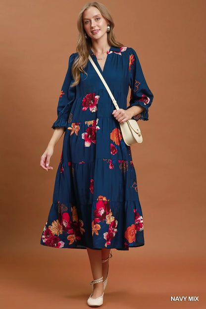 Woman wearing an Umgee navy floral tiered midi dress with puff sleeves, pockets, and a flowy feminine silhouette.