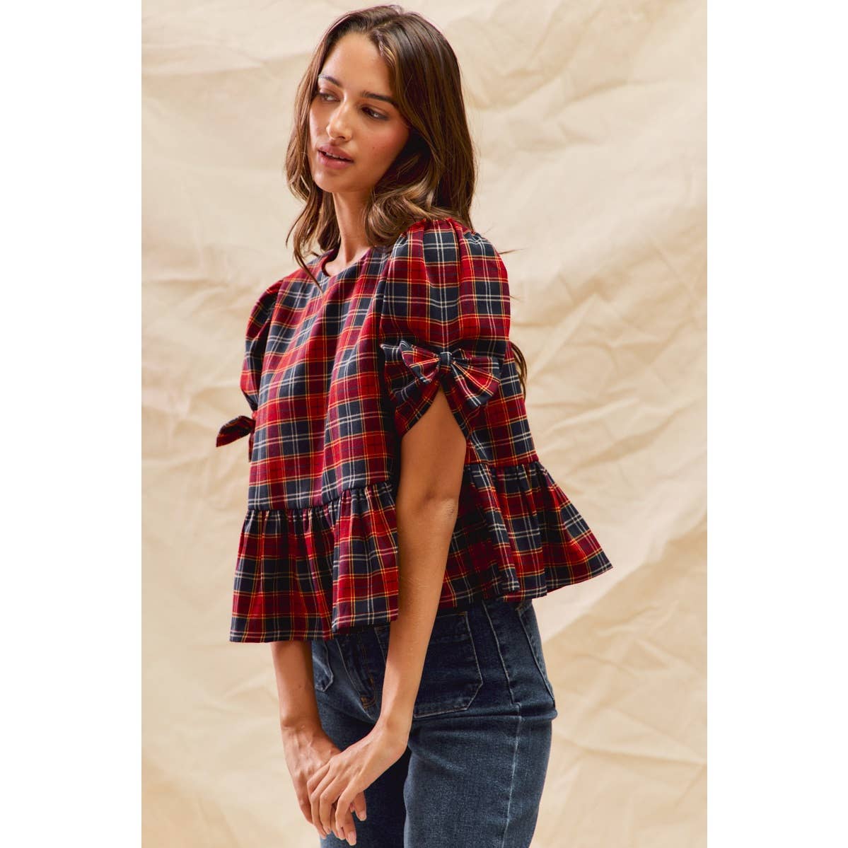 So Me Christmas red and navy plaid peplum top with puff sleeves and ribbon bow details on a model