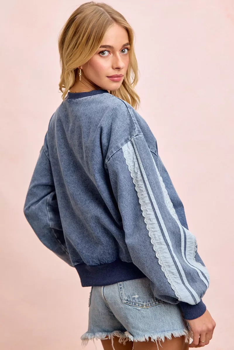 Woman wearing a washed denim lace contrast sweatshirt with long sleeves and relaxed fit by BiBi.