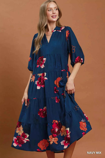 Woman wearing an Umgee navy floral tiered midi dress with puff sleeves, pockets, and a flowy feminine silhouette.