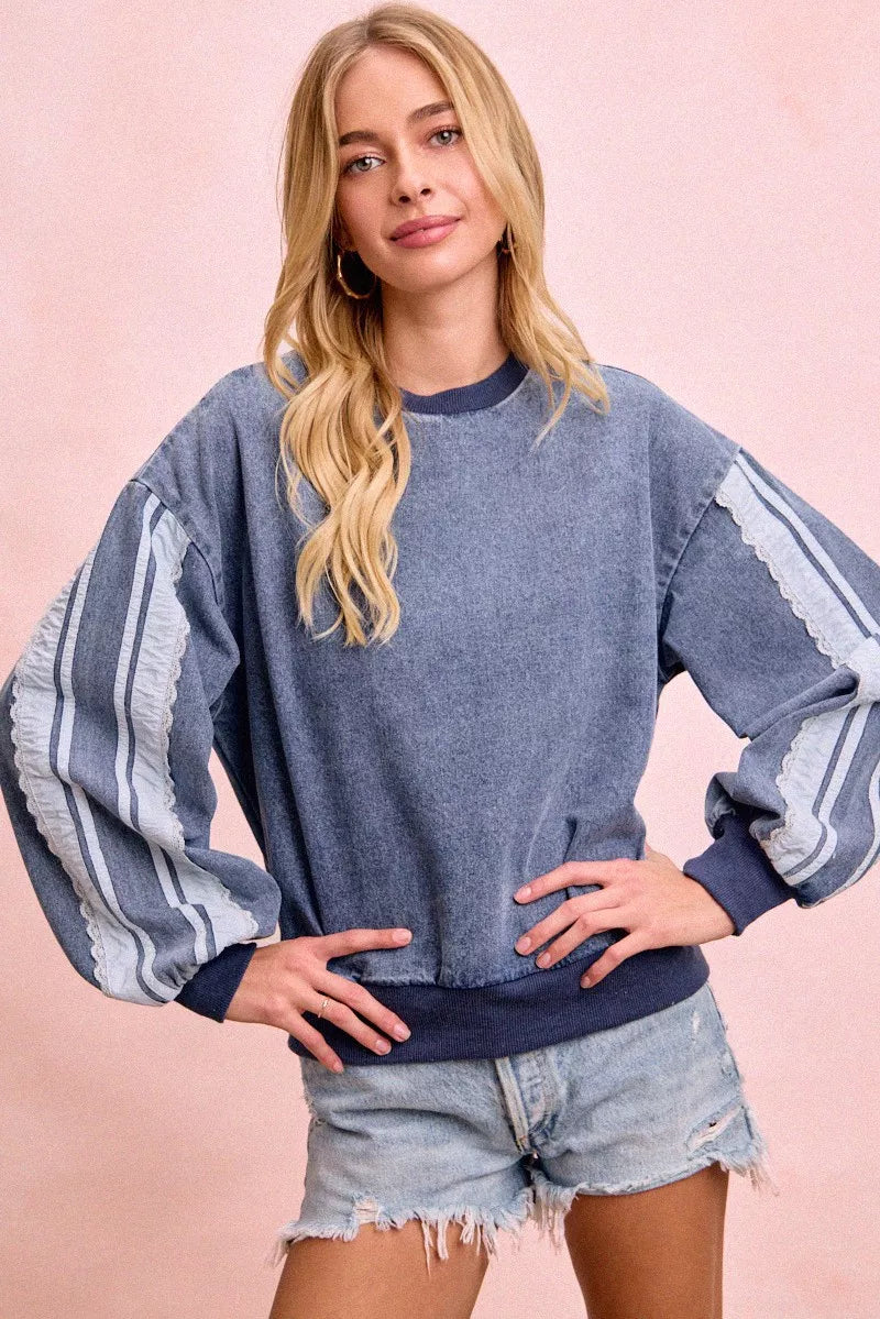 Woman wearing a washed denim lace contrast sweatshirt with long sleeves and relaxed fit by BiBi.